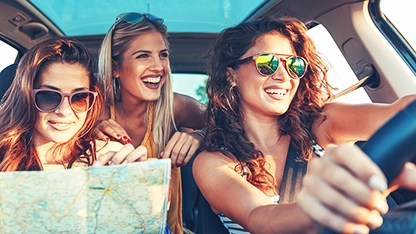 Tre donne sorridenti in auto durante un viaggio