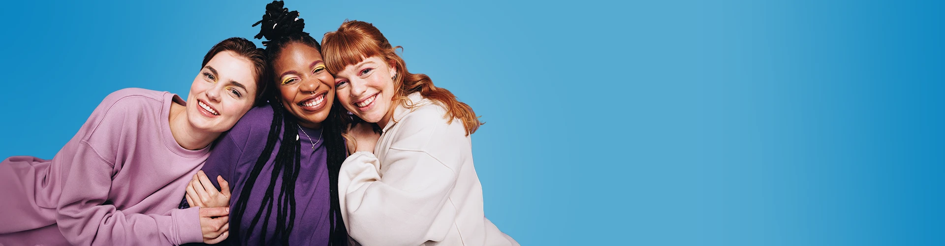 Tre donne sorridenti appoggiate l'una all'altra