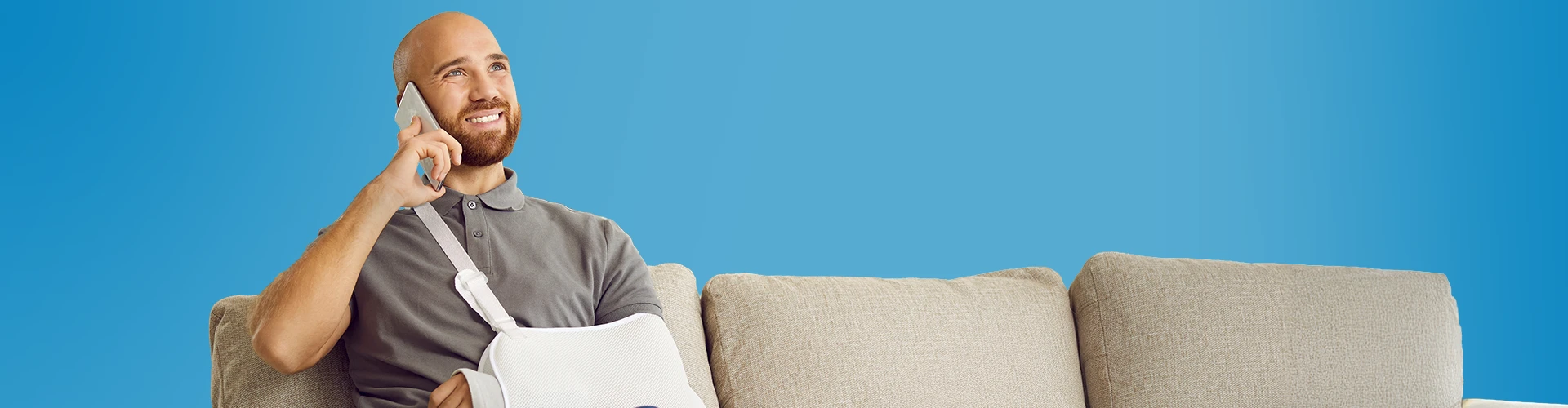 Uomo sorridente con un braccio rotto che parla al telefono