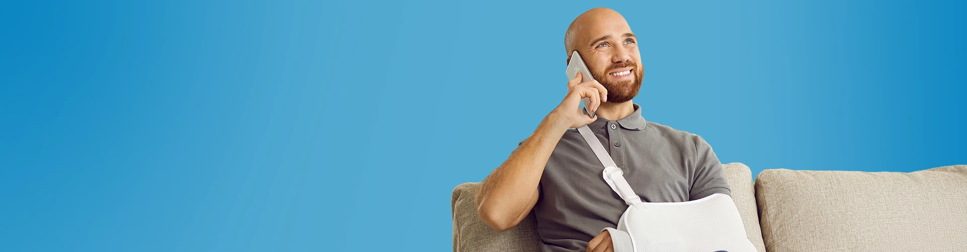 Uomo sorridente con un braccio rotto che parla al telefono