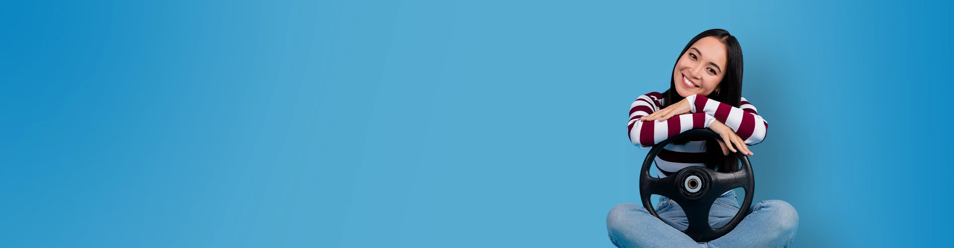 Donna sorridente seduta a gambe incrociate con le braccia appoggiate su un volante