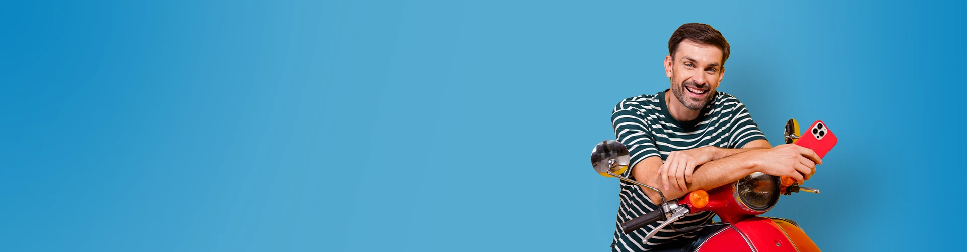 Uomo sorridente appoggiato su un motociclo Vespa con in mano uno smartphone