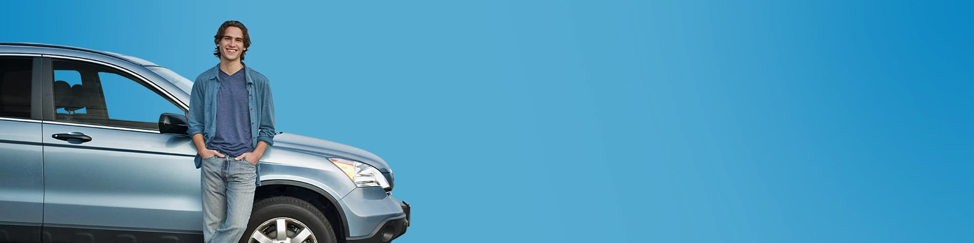 Giovane uomo sorridente appoggiato ad una macchina