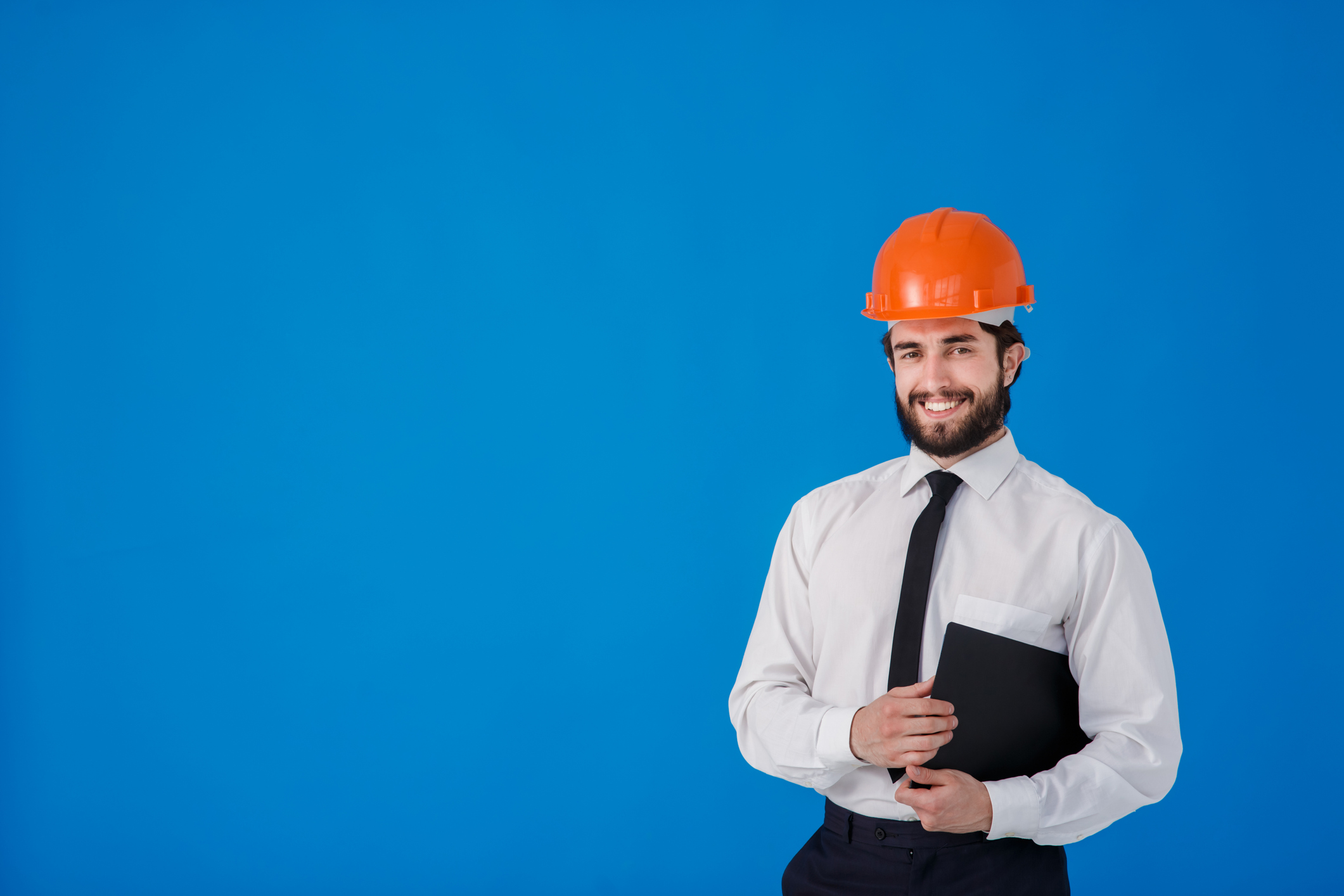 Uomo sorridente in camicia bianca e caschetto protettivo arancione