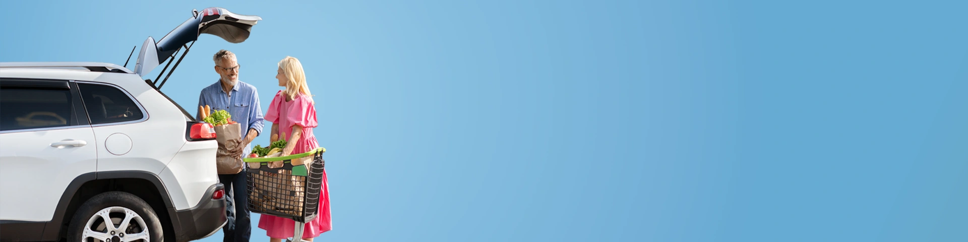 Uomo e donna con carrello della spesa che la caricano nel baule della macchina