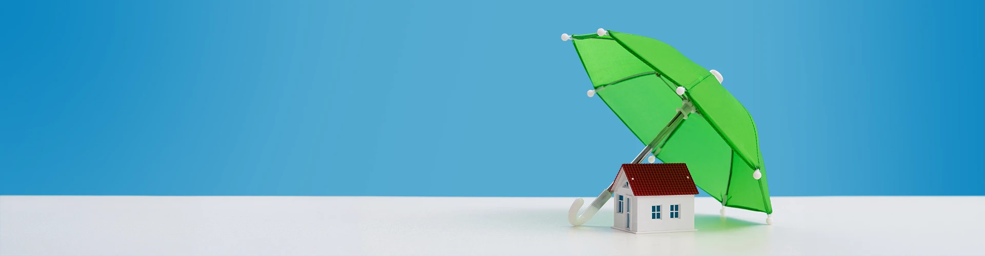 Modellino di casa coperto da un ombrello verde