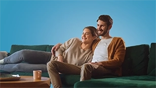 Uomo e donna sorridenti abbracciati sul divano