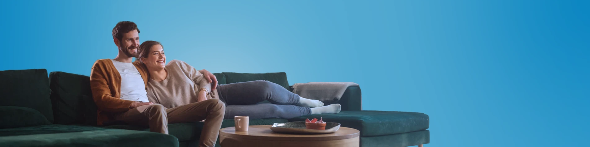 Uomo e donna sorridenti abbracciati sul divano