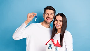 Un uomo e una donna sorridenti con in mano un modellino di casa e un mazzo di chiavi