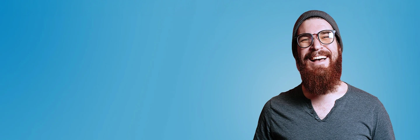 Giovane uomo sorridente con baba, occhiali e cappello