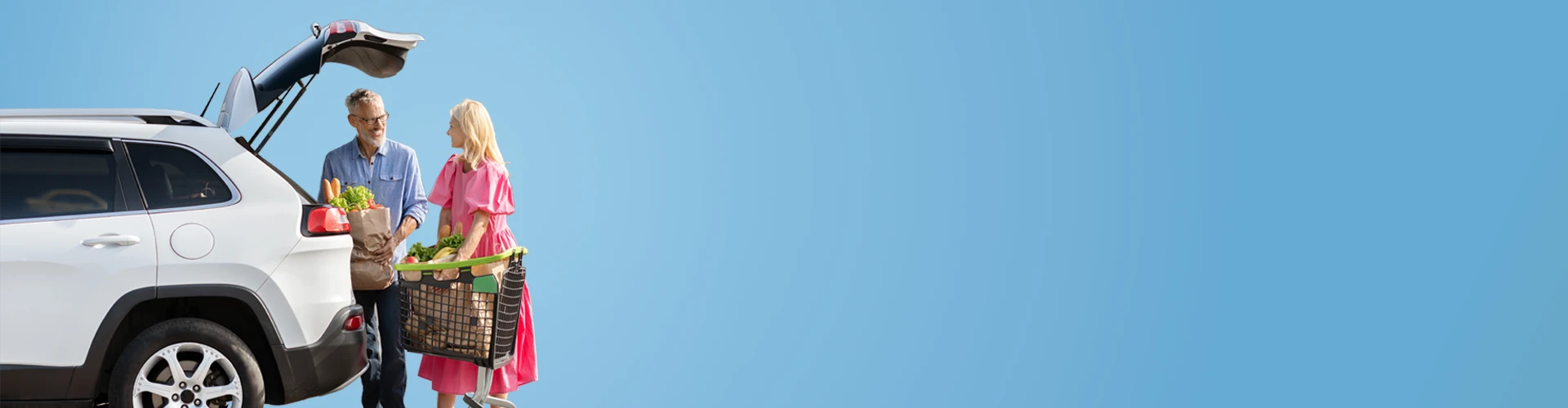 Uomo e donna con carrello della spesa che la caricano nel baule della macchina