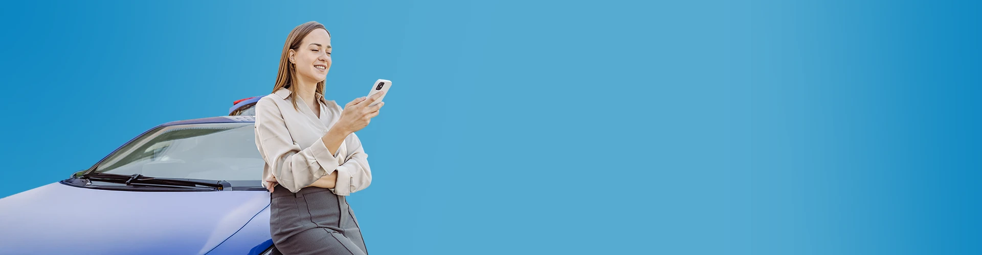 Donna appoggiata all'auto che sta guardando lo smartphone che tiene in mano